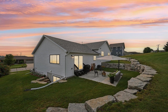 back house at dusk featuring a lawn and a patio