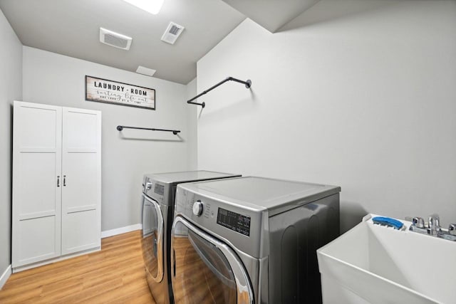 washroom featuring sink, washing machine and dryer, and light wood-type flooring