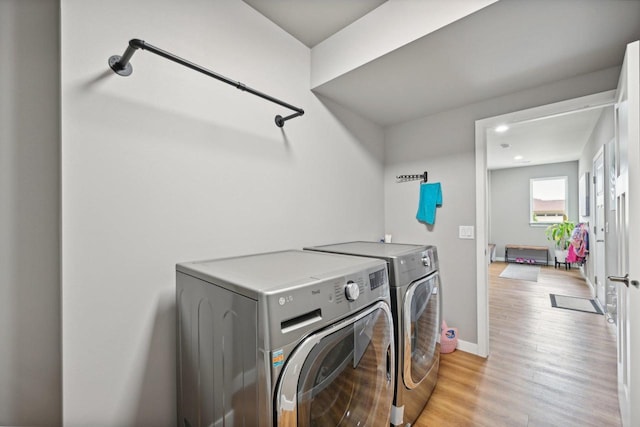 laundry room with light wood-type flooring and washing machine and clothes dryer