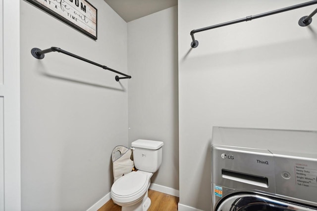 bathroom featuring washer / dryer, toilet, and wood-type flooring