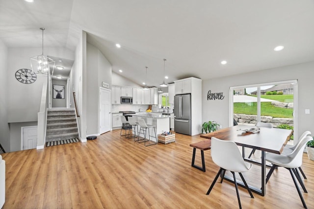 dining room with lofted ceiling, light wood-type flooring, and a notable chandelier