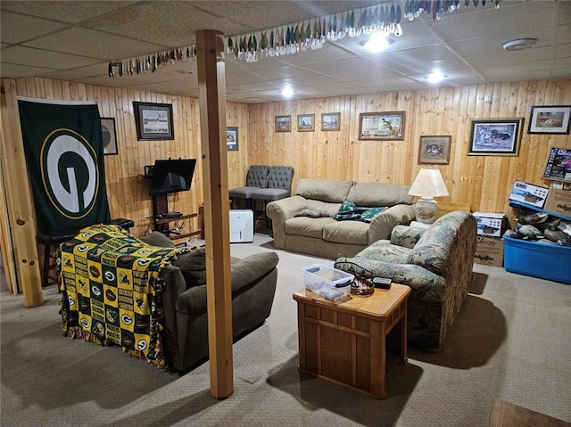 living room featuring wood walls, a paneled ceiling, and carpet floors