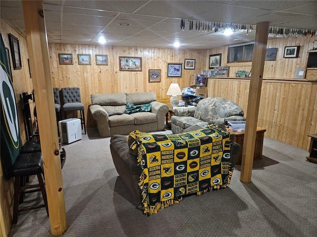 carpeted living room featuring a paneled ceiling and wood walls