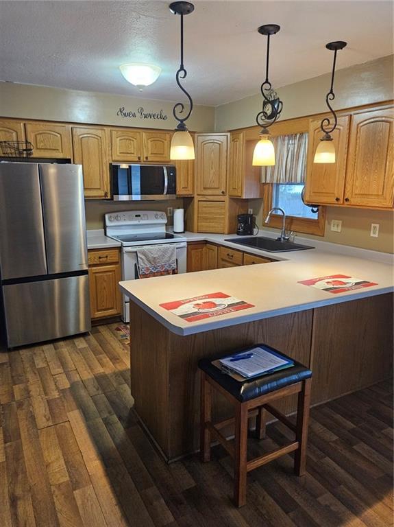 kitchen featuring stainless steel appliances, sink, a kitchen breakfast bar, hanging light fixtures, and kitchen peninsula