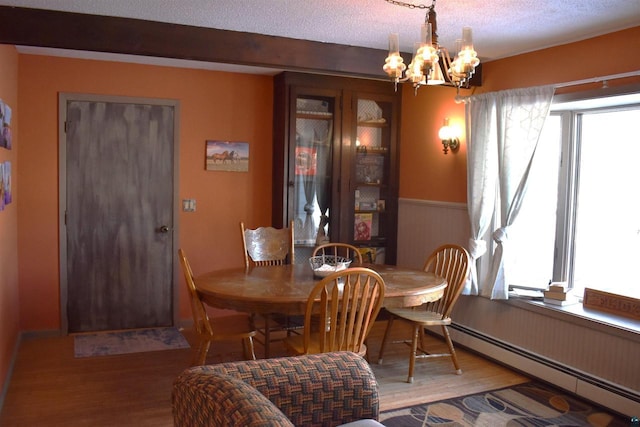 dining room with a baseboard radiator, wood-type flooring, a wealth of natural light, and a chandelier