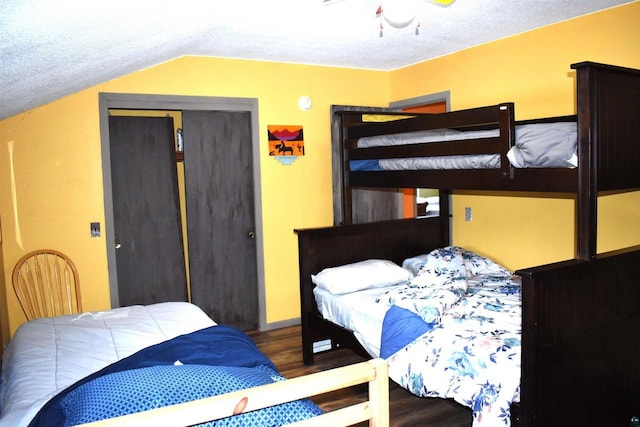 bedroom with a textured ceiling, wood-type flooring, a closet, vaulted ceiling, and ceiling fan