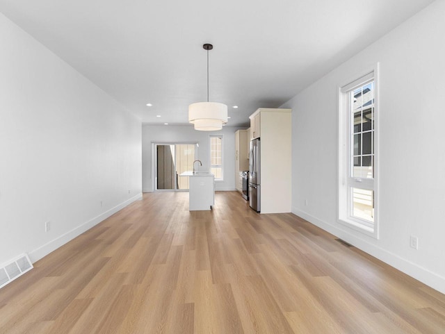 unfurnished living room featuring light wood-type flooring and plenty of natural light