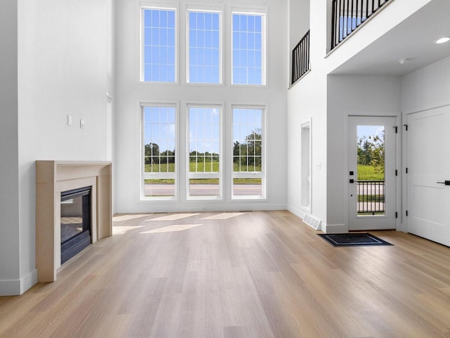 unfurnished living room featuring a towering ceiling and light hardwood / wood-style floors