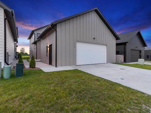 garage at dusk featuring a yard