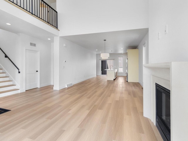 unfurnished living room with a towering ceiling and light hardwood / wood-style flooring