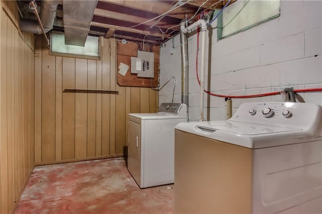 laundry room with washer and clothes dryer, wood walls, and electric panel