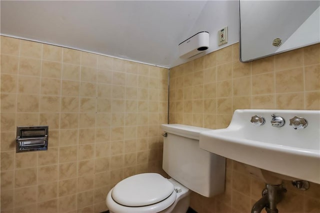 bathroom with sink, tile walls, and toilet