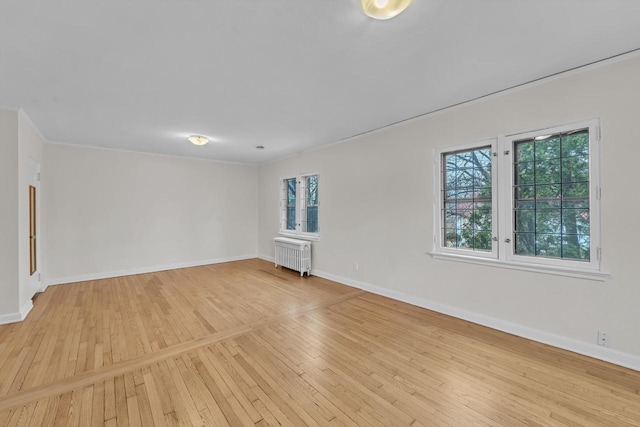 unfurnished room featuring a wealth of natural light, radiator, and light hardwood / wood-style flooring