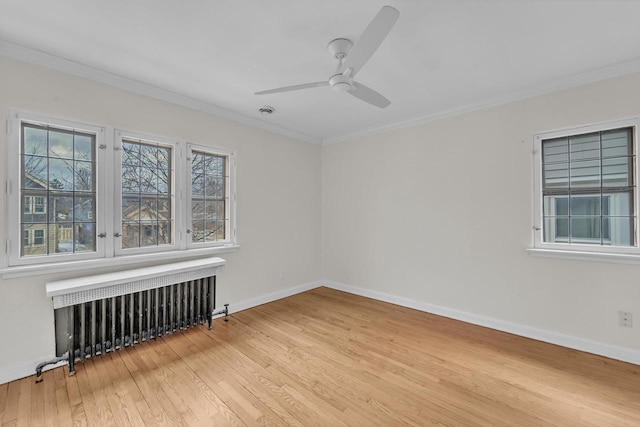 spare room featuring light wood-type flooring, ceiling fan, ornamental molding, and radiator heating unit