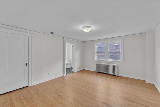 empty room with light hardwood / wood-style floors and radiator