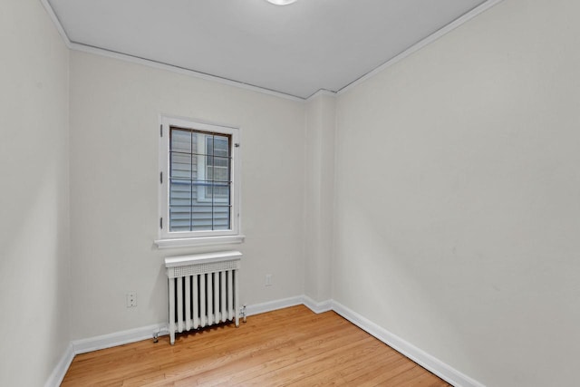 unfurnished room with light hardwood / wood-style floors, radiator heating unit, and crown molding