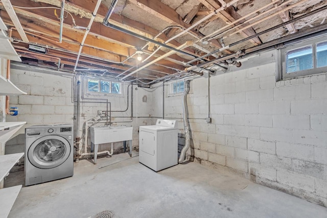 basement featuring a healthy amount of sunlight, washing machine and dryer, and sink