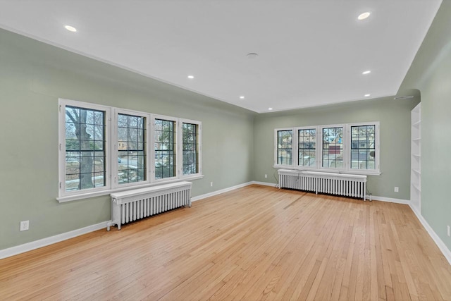 spare room with radiator heating unit and light hardwood / wood-style flooring