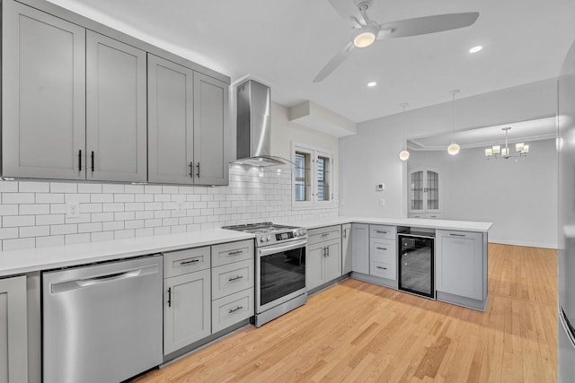 kitchen featuring stainless steel appliances, wall chimney exhaust hood, wine cooler, and gray cabinets