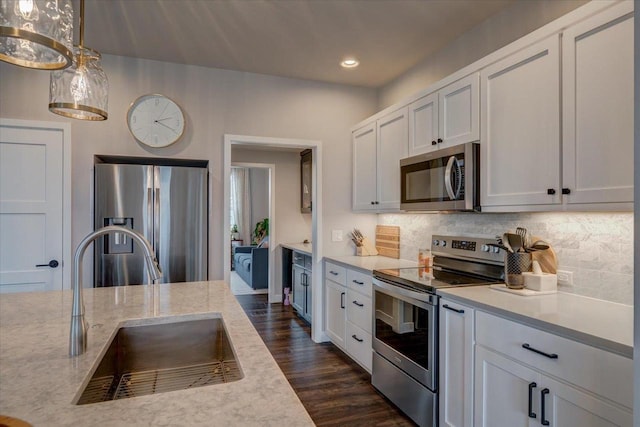 kitchen with stainless steel appliances, white cabinetry, decorative light fixtures, and sink