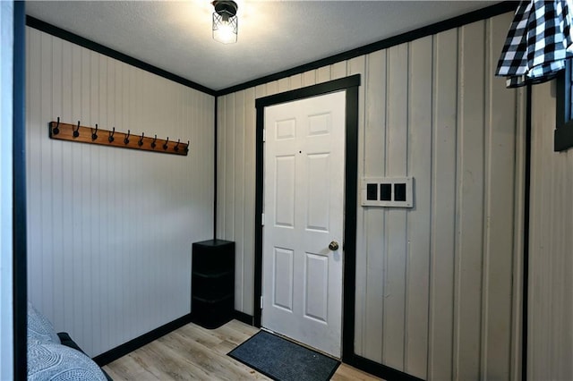 interior space featuring light wood-type flooring, a textured ceiling, and crown molding