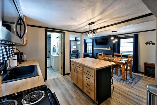 kitchen featuring a kitchen island, a kitchen bar, hanging light fixtures, ornamental molding, and butcher block counters