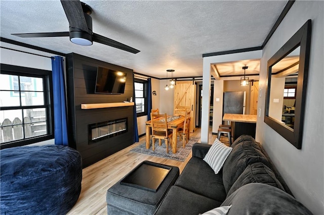 living room featuring light wood-type flooring, ornamental molding, a barn door, and a large fireplace