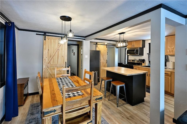 dining area with light hardwood / wood-style floors, crown molding, and a barn door