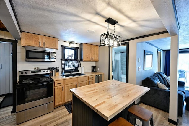 kitchen with hanging light fixtures, a wealth of natural light, appliances with stainless steel finishes, and sink