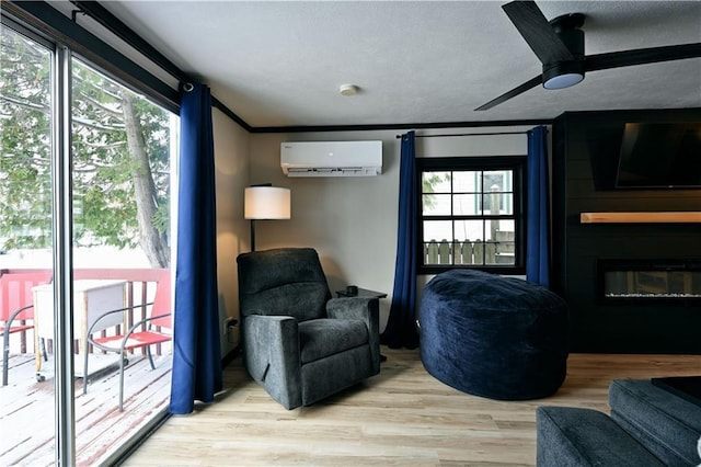 living area featuring ceiling fan, an AC wall unit, a fireplace, light wood-type flooring, and ornamental molding