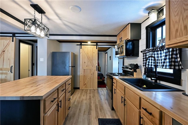 kitchen with a barn door, butcher block countertops, light hardwood / wood-style flooring, hanging light fixtures, and stainless steel appliances