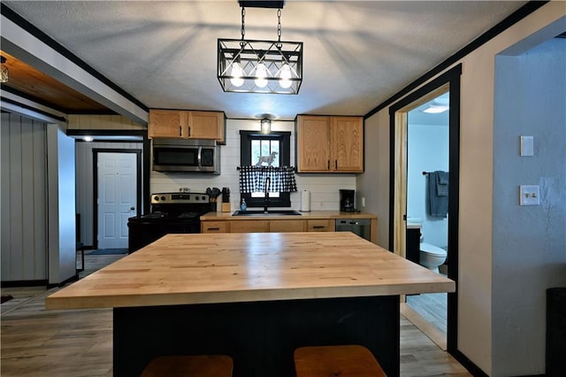 kitchen featuring a textured ceiling, a center island, butcher block counters, hanging light fixtures, and electric range