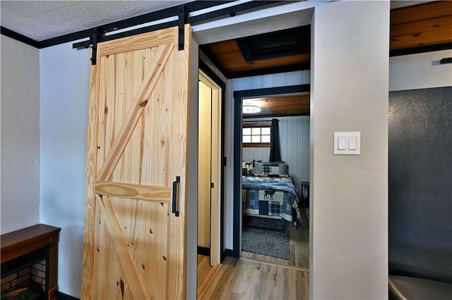 hall with a barn door, a textured ceiling, and hardwood / wood-style floors