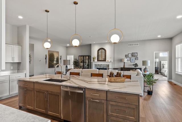 kitchen with hanging light fixtures, dishwasher, sink, and white cabinetry