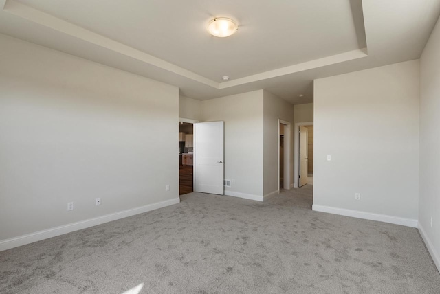 carpeted spare room featuring a raised ceiling