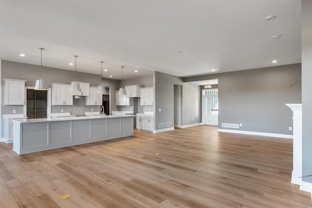 kitchen featuring decorative light fixtures, a spacious island, and white cabinets