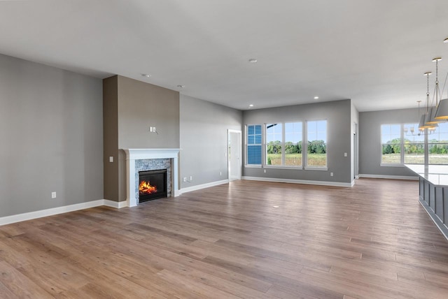 unfurnished living room with a stone fireplace and light hardwood / wood-style flooring