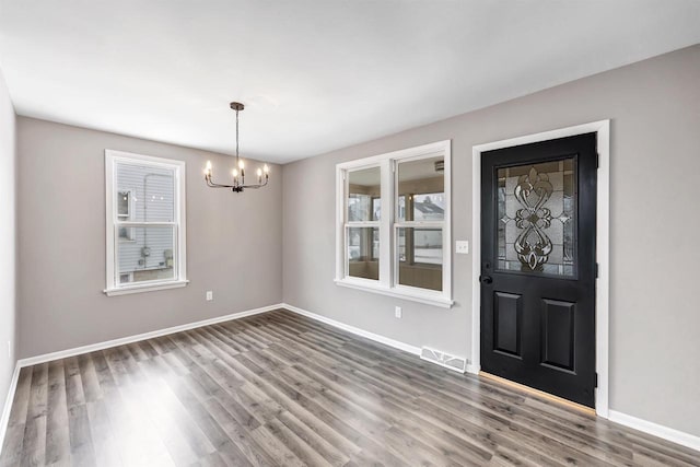 foyer with wood-type flooring, a healthy amount of sunlight, and an inviting chandelier