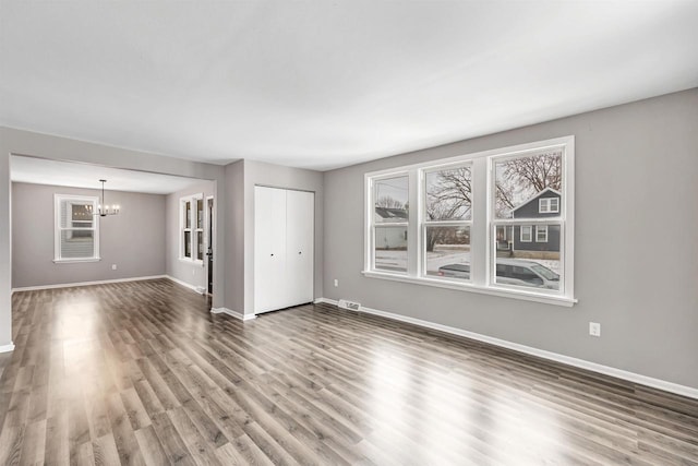 unfurnished living room with dark hardwood / wood-style floors and an inviting chandelier