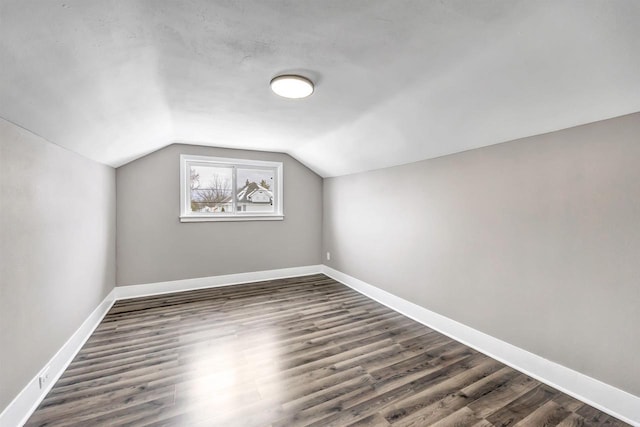 bonus room with vaulted ceiling and dark wood-type flooring