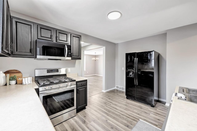 kitchen featuring appliances with stainless steel finishes, light hardwood / wood-style flooring, and an inviting chandelier