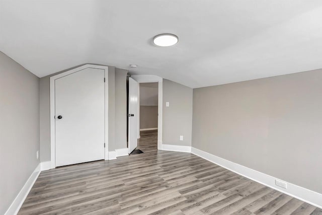 additional living space with vaulted ceiling and light hardwood / wood-style flooring