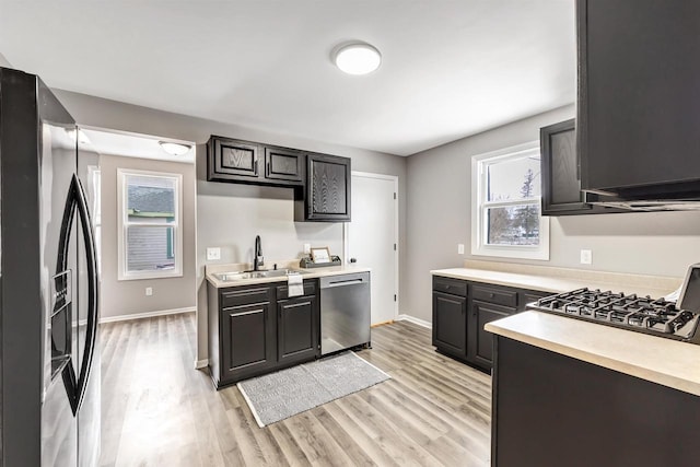 kitchen featuring refrigerator with ice dispenser, light wood-type flooring, gas stovetop, dishwasher, and sink