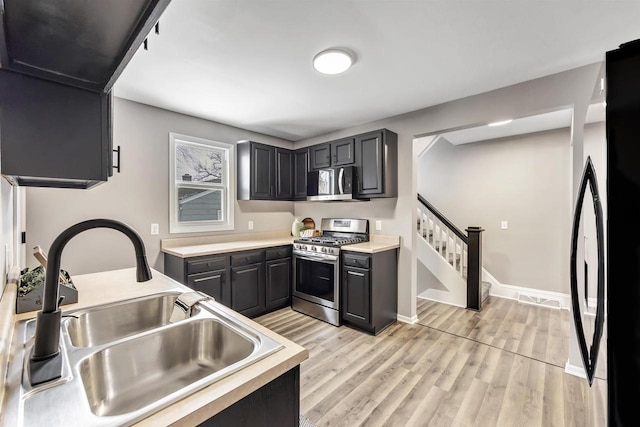 kitchen with appliances with stainless steel finishes, sink, and light hardwood / wood-style floors