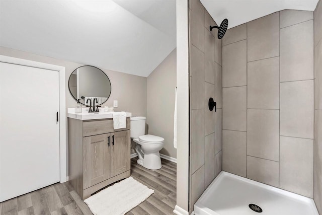 bathroom with wood-type flooring, toilet, vanity, and a tile shower