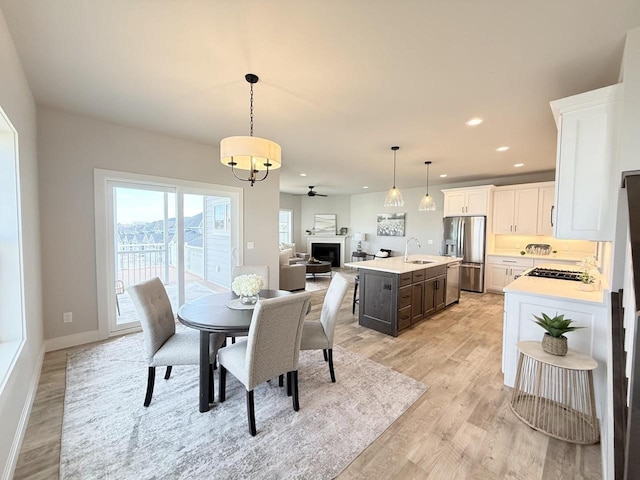 dining area with ceiling fan, light hardwood / wood-style floors, and sink