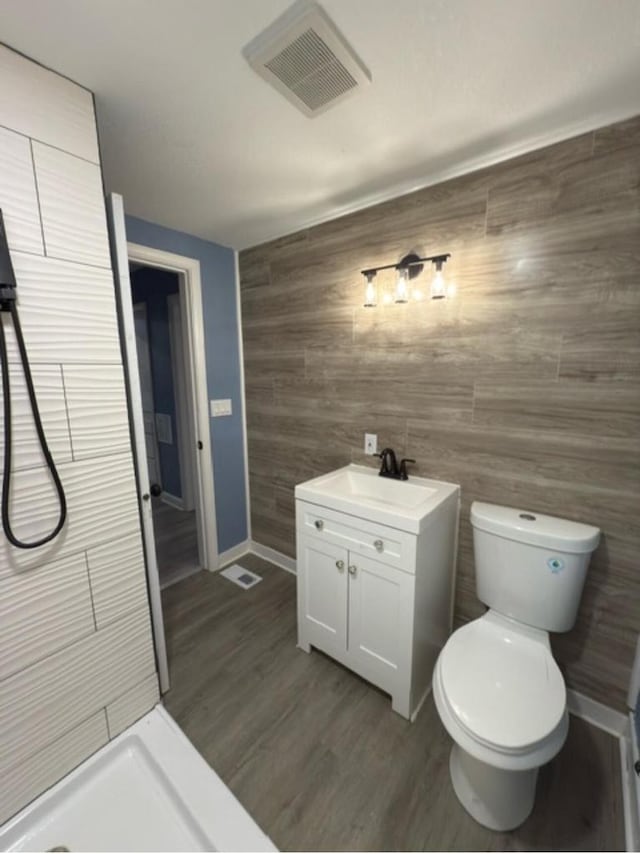 bathroom with toilet, vanity, a shower, and hardwood / wood-style flooring