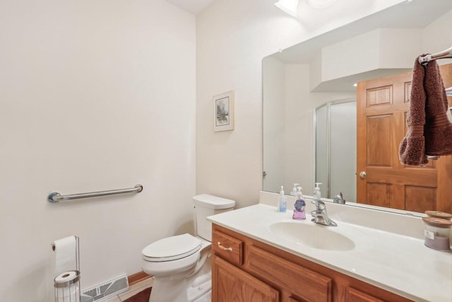 bathroom featuring toilet, vanity, tile patterned flooring, and a shower with door