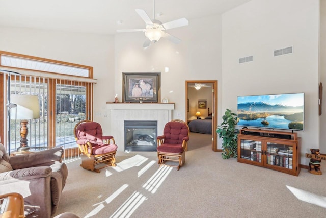 living room featuring high vaulted ceiling, a tiled fireplace, ceiling fan, and carpet flooring