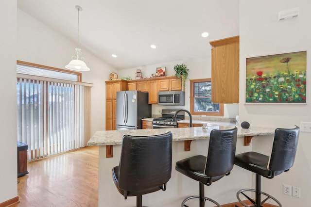 kitchen with kitchen peninsula, a wealth of natural light, light stone counters, and stainless steel appliances